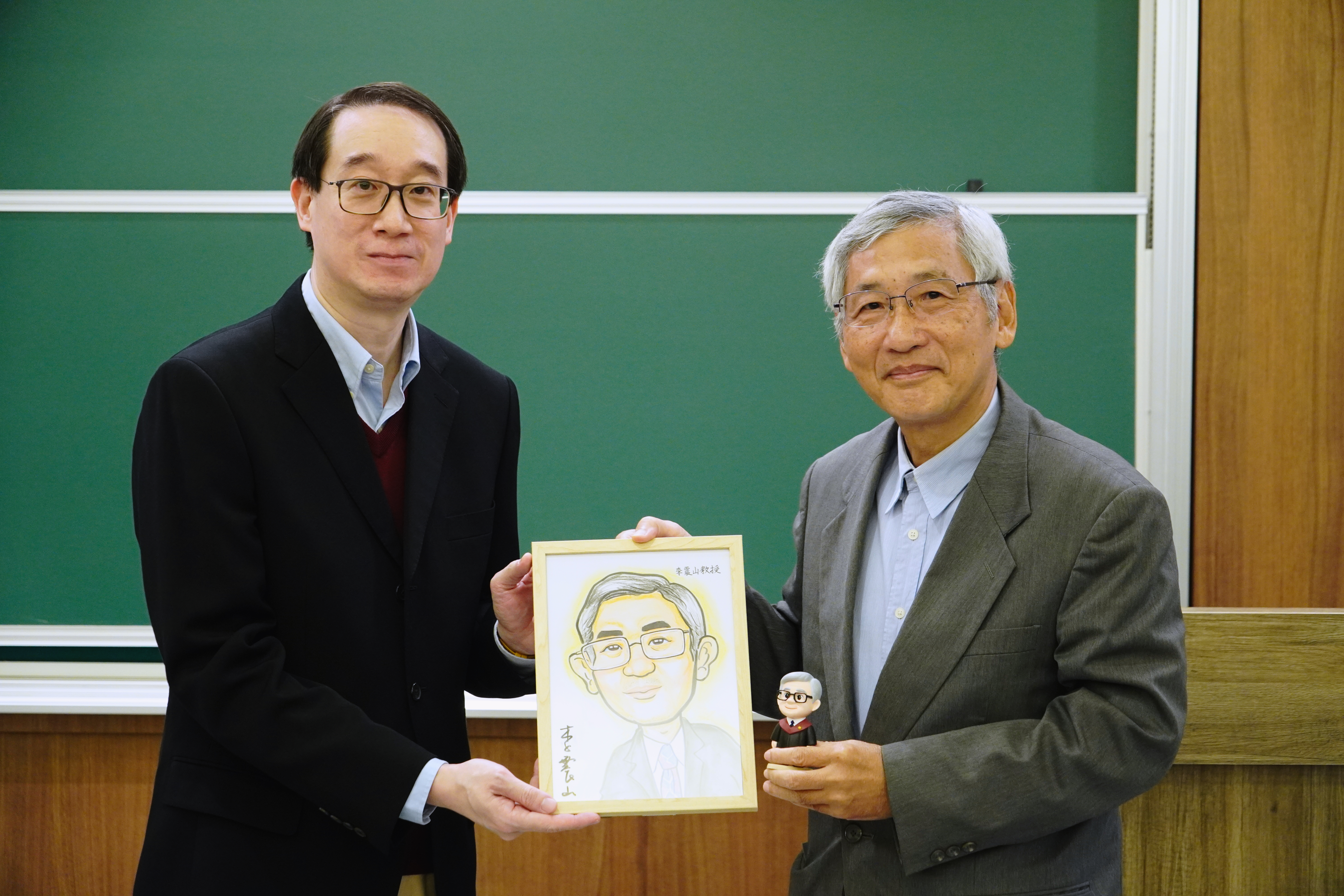 劉定基教授（左）頒贈紀念品形象公仔與似顏繪與李震山教授（右）。