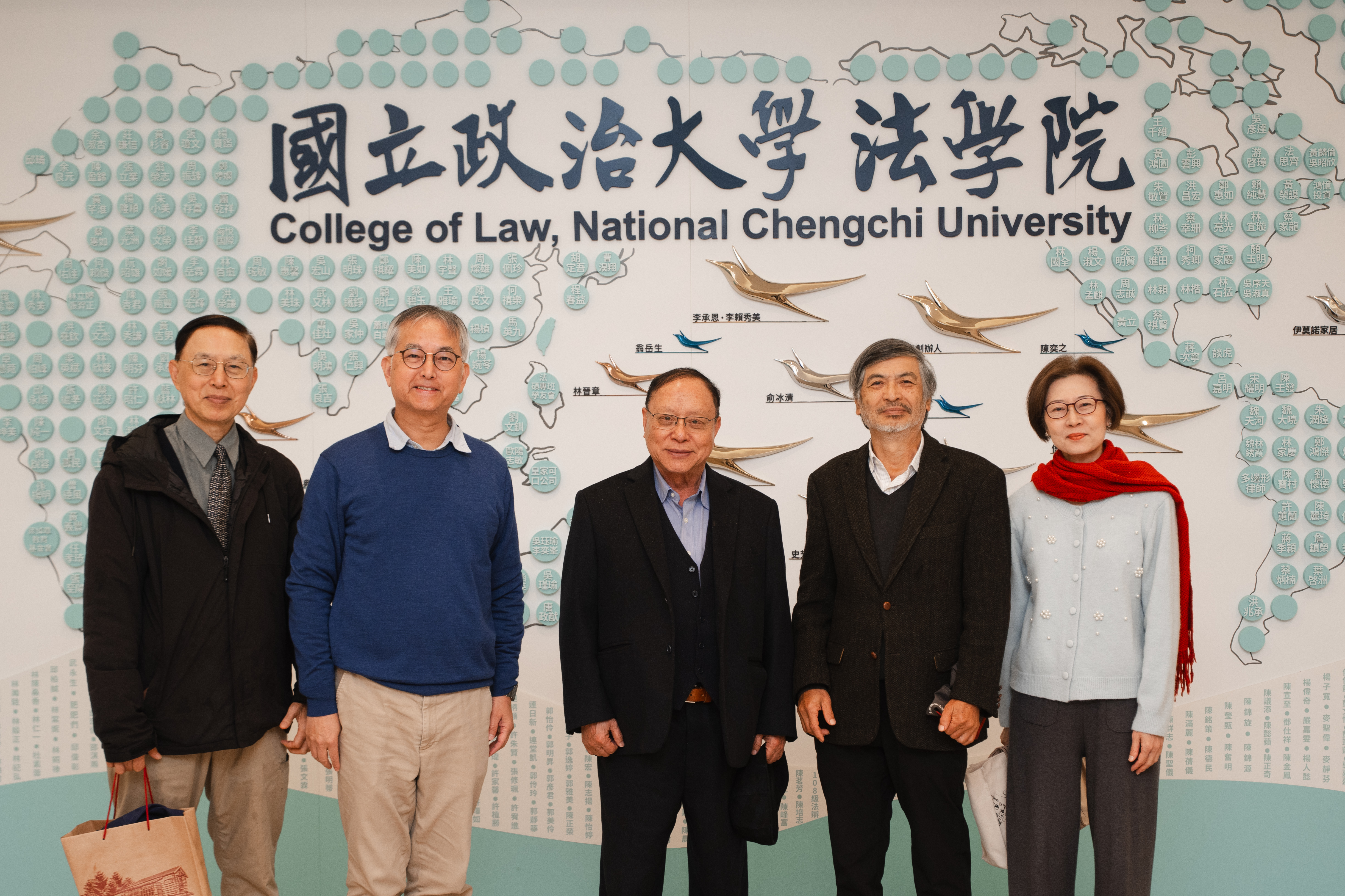 王順忠經理（左一）、王文杰前副校長（左二）、芶壽生學長（中）、郭明政前校長（右二）、吳瑾瑜院長（右一）於法學院感恩牆前合影。