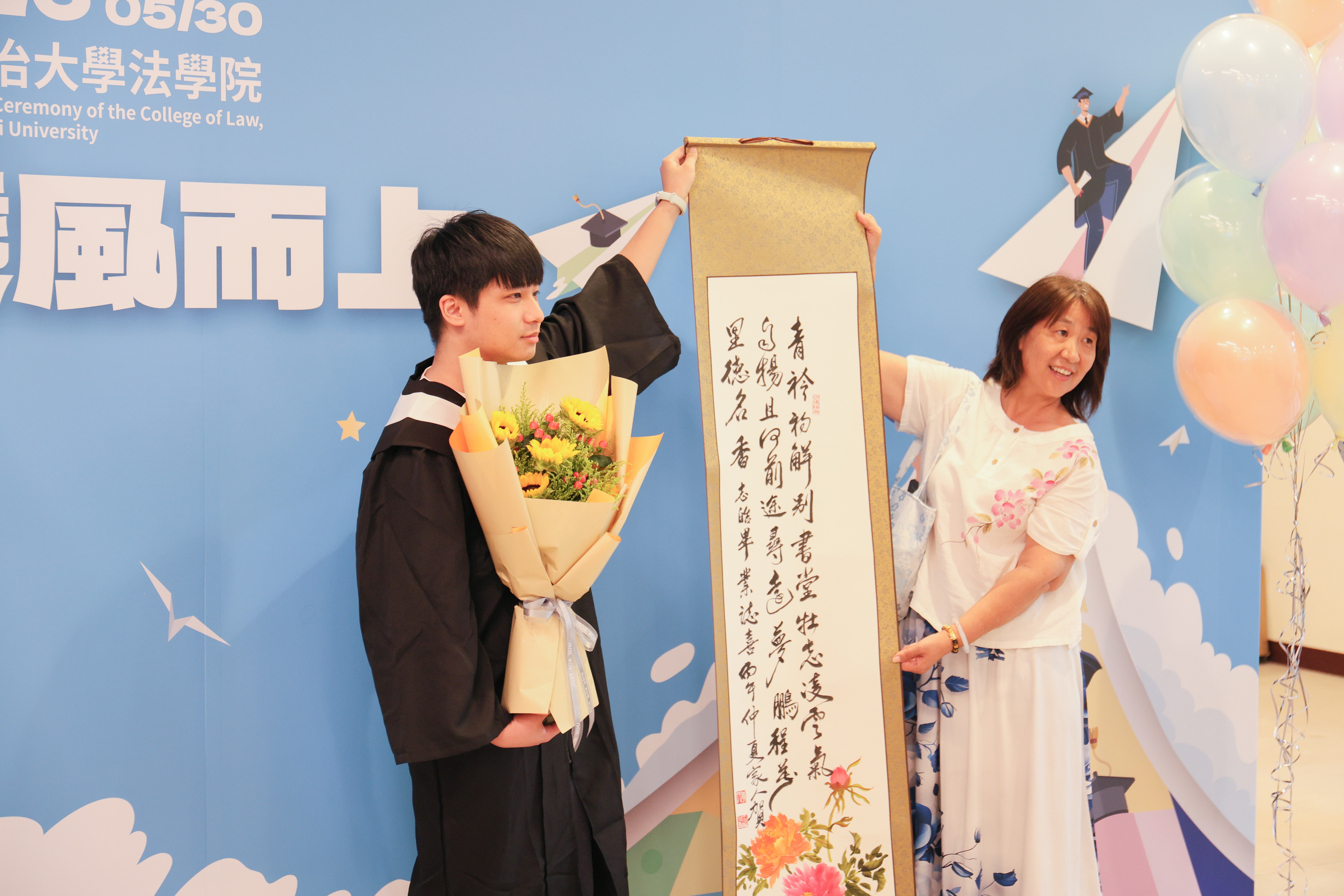 畢業生於法學院大廳背板前留影。